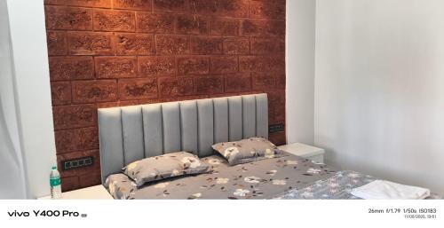 a bed in a room with a brick wall at Sai Holliday's home in Alibaug