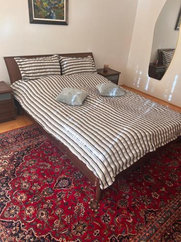 a bed with two pillows on top of a red rug at Atila Nature Home in Bjelašnica
