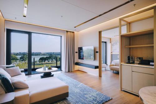 蘇州市にあるSuzhou Marriott Hotel Yangcheng Lakeのソファと大きな窓のあるリビングルーム