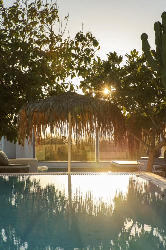 ein Schwimmbecken mit einem Strohschirm und Bäumen in der Unterkunft La Stella Stay in Glastros