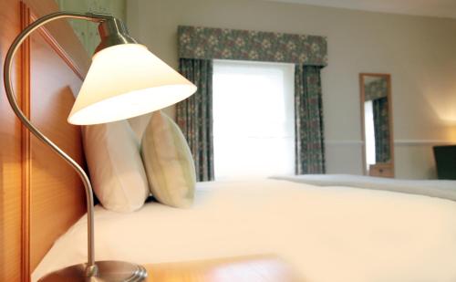 a bedroom with a bed with a lamp and a window at Victoria Square Hotel Clifton Village in Bristol