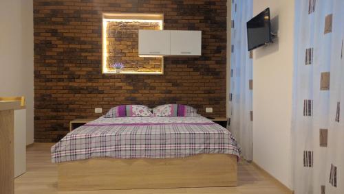 a bedroom with a bed and a brick wall at BrasovApart Piata Sfatului in Braşov