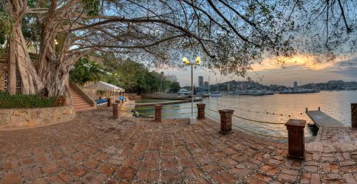 a brick walkway next to a river with a tree at Alba Suites Acapulco in Acapulco