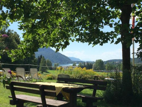 a picnic table and chairs under a tree at Georgihof im Park in Unterburg am Klopeiner See
