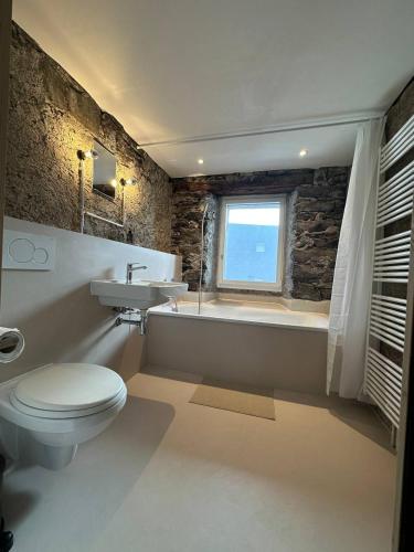 a bathroom with a toilet and a sink and a bath tub at Historische Unterkunft Casa Tre Valli in Biasca