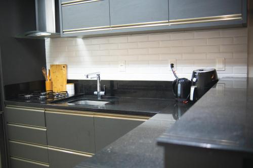 コンボリウーにあるCasa com Jacuzzi, Próximo Teleférico, GreenValley e Praia BC!のシンクとカウンタートップのあるキッチン