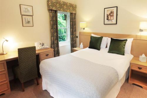 a hotel room with a bed and a desk and a window at Victoria Square Hotel Clifton Village in Bristol