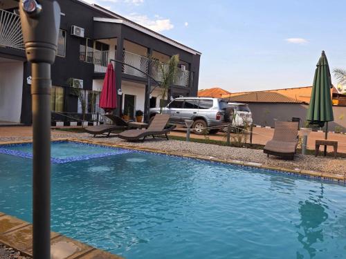 a pool with chairs and umbrellas next to a building at sarahs apartments solwezi in Mpemba