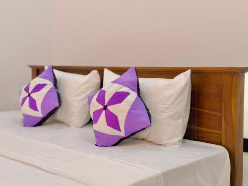 four pillows on a bed with purple and white pillows at Akarsha Residence in Negombo