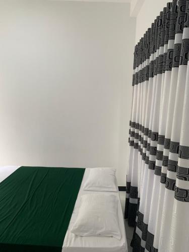 a bedroom with a bed with a green and white curtain at Wilpattu Nuga Lodge in Pahala Maragahawewa