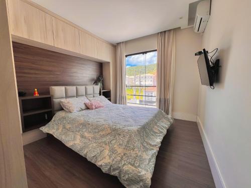 コンボリウーにあるCasa com Jacuzzi, Próximo Teleférico, GreenValley e Praia BC!のベッドと大きな窓のある寝室