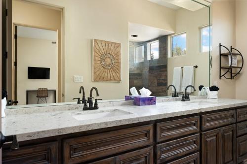 a bathroom with two sinks and a large mirror at Barwick is a private oasis Practice on the putting green shoot pool and enjoy this city getaway. in Scottsdale
