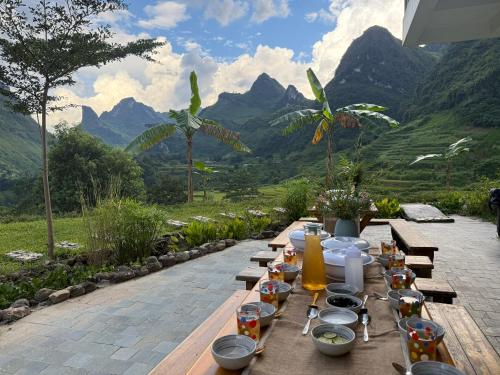 a wooden table with food on it with mountains in the background at Jashill Homestay in Yên Minh
