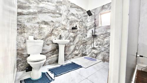 a bathroom with a toilet and a stone wall at Jacaranda Escape in Pretoria