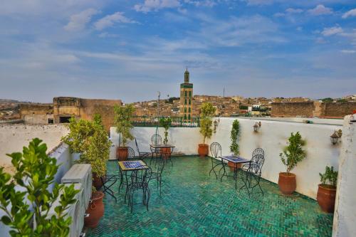 a balcony with tables and chairs and a view of a city at Dar Elinor Fez in Fès