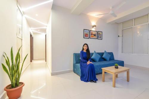 una mujer sentada en un sofá azul en una sala de estar en Via The Max Glory, en Indore