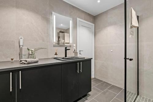 a bathroom with a sink and a shower at Delikat, romslig og sjønær sentrumsleilighet in Larvik