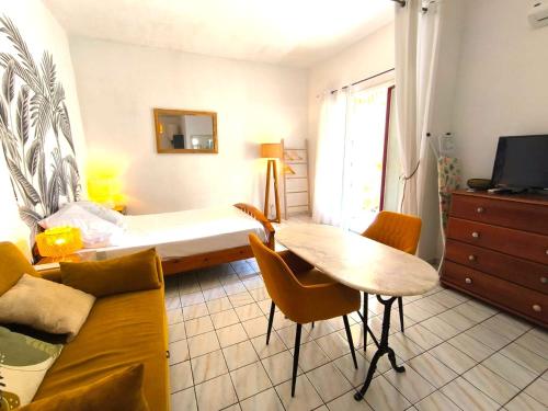 a living room with a bed and a table and chairs at Le Rodrigues - plages - parking - clim - wifi in Saint-Gilles les Bains