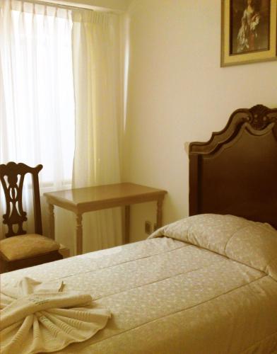 a bedroom with a bed and a chair and a window at San Marino Royal Hotel in Sucre