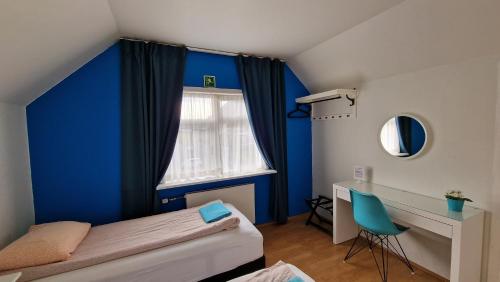 1 dormitorio con una pared azul, 1 cama y escritorio en Grundarfjördur Hostel, en Grundarfjordur