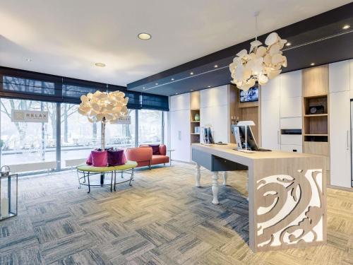 a lobby with a desk and a couch at Mercure Hotel Hannover Mitte in Hannover