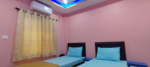 two beds in a room with pink walls at Nirmal Guest House in Marakkānam