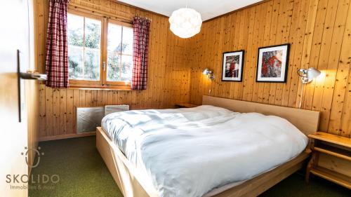 a bedroom with a bed in a wooden wall at Chalet Dorle, Riederalp Golmenegg in Riederalp