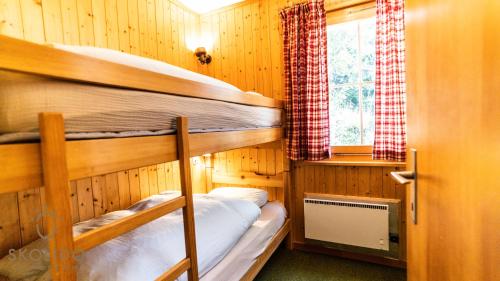 Un dormitorio con dos literas y una ventana. en Chalet Dorle, Riederalp Golmenegg, en Riederalp