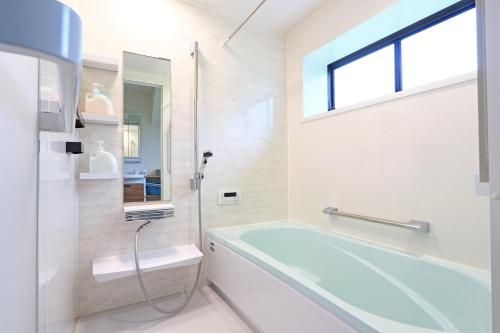 een badkamer met een bad, een wastafel en een spiegel bij コテージ鎌倉 in Fujikawaguchiko