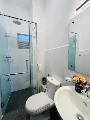 a bathroom with a toilet and a glass shower at Casa Santorini Negombo Resort Apartment in Negombo