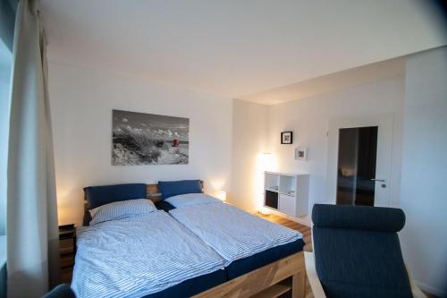 een slaapkamer met een blauw bed en een stoel bij Ruhige See in Borkum