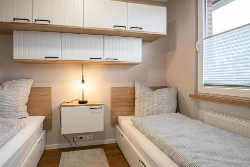 a bedroom with two beds and a table with a lamp at fien un moje in Borkum
