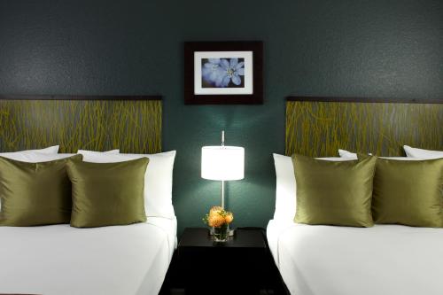 two beds in a hotel room with green walls at Skyline Island Colony Hotel in Honolulu