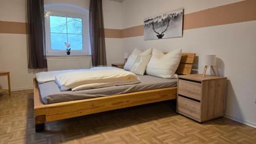 ein Schlafzimmer mit einem Holzbett, einem Fenster und einem Tisch in der Unterkunft Ferienwohnung Aschenbrenner in Hohenwarth