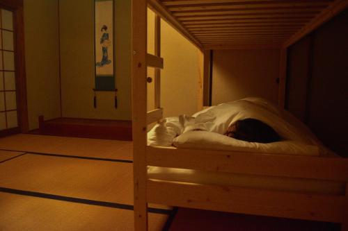 een persoon ligt in een stapelbed bij ゲストハウス灯 in Azumino