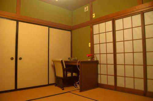 een kamer met een bureau en een tafel met een stoel bij ゲストハウス灯 in Azumino