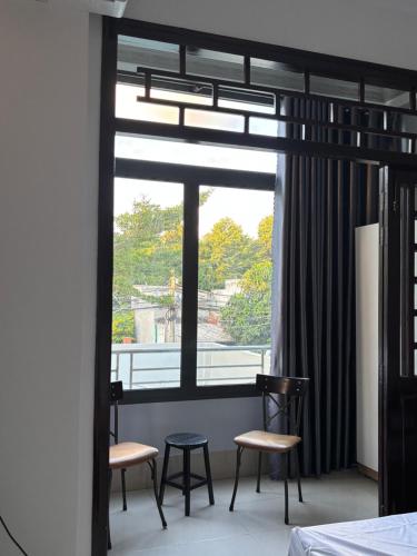 Zimmer mit 2 Stühlen und einem großen Fenster in der Unterkunft Nhà Nghỉ Đăng Khoa in Ấp Thiện Sơn