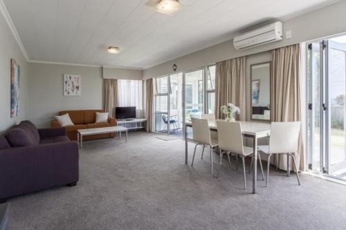 a living room with a couch and a table with chairs at Sea Breeze On Belt - near beach & coastal walk in New Plymouth