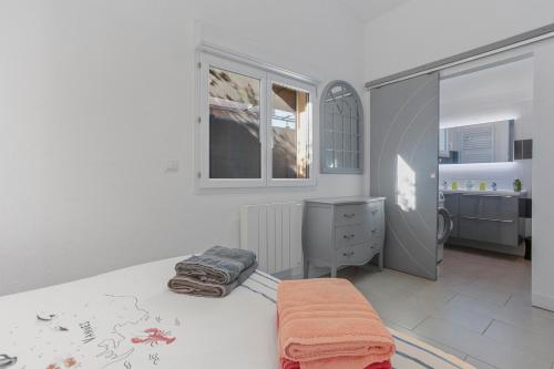 a white bedroom with a bed and a dresser at Les Sables in Bormes-les-Mimosas