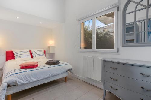 a bedroom with a bed with a dresser and a window at Les Sables in Bormes-les-Mimosas