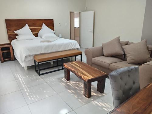 Un dormitorio con una cama, un sofá y una mesa. en Wildlife Oasis, en Marloth Park