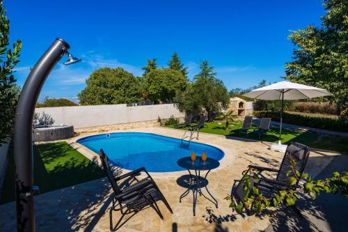 a pool with two chairs and a table and an umbrella at My Dalmatia - Holiday home Emily with private pool in Raštević