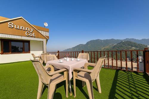 una mesa y sillas en el balcón de un restaurante en Hotel Sunny Cot - Free Mall Shuttle and Parking, en Mussoorie