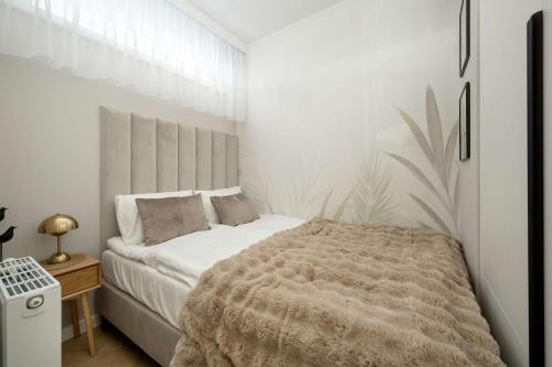 ein weißes Schlafzimmer mit einem Bett und einem Tisch in der Unterkunft Elegant Apartments Mieszczańska Wrocław with Air Conditioning, Spa & Gym by Renters Prestige in Breslau