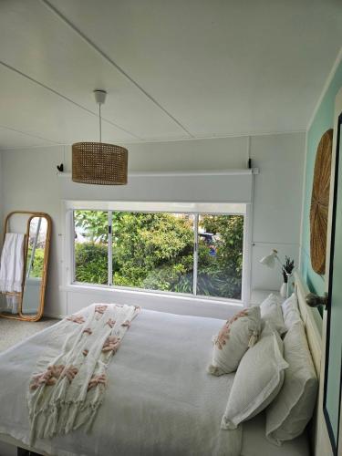 a bedroom with a large bed with a large window at Port Sorell Beach Shack in Port Sorell