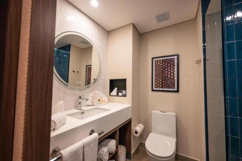 a bathroom with a sink and a toilet and a mirror at Hotel Hampton By Hilton Santiago De Los Caballeros in Santiago de los Caballeros