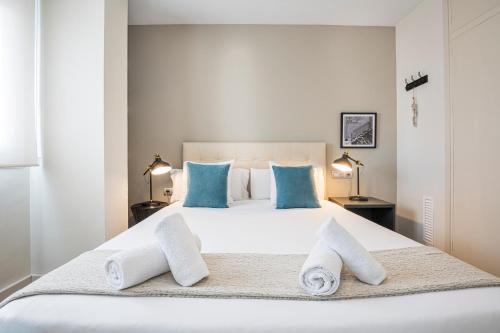 a bedroom with a large white bed with blue pillows at Sitges Spaces Oasis Penthouse 3 Bedroom, 2 Bathroom, Terrace, Pool, Sleeps up to 6 in Sitges