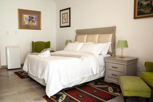 a bedroom with a white bed and a green chair at Miyanwe in Pretoria