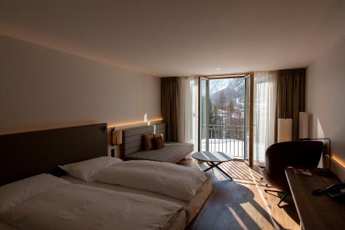a hotel room with a bed and a balcony at Hotel Saratz Pontresina Mountain Resort & Spa in Pontresina