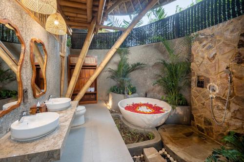 een badkamer met 2 wastafels en een groot bad bij Emana Bambooscape in Ubud